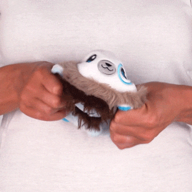 Hands putting batteries into a Casting Shadows: Frost Polarpaw & Frost the Merciless Reversible Plushie that's lying on someone's lap, made by Unstable Games.