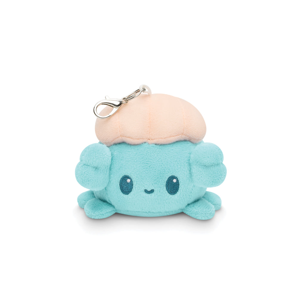 The Dribble Plushie Charm Keychain by Unstable Games is a small, cute, blue crab plush toy with a beige top and a metal clip at the top.