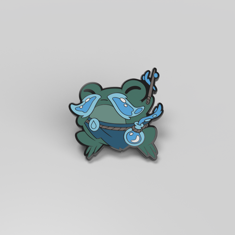 Torrent the Droplet Sage Enamel Pin from Unstable Games features a cartoonish blue and green frog with exaggerated features, including bulging eyes and large limbs, set against a plain white background. The frog appears to be holding small metal and enamel objects, making it perfect for adding a playful touch to bags.