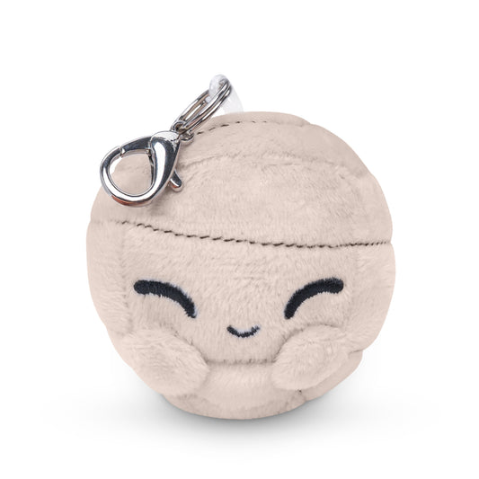 A round, beige plush keychain with a smiling face and closed eyes, featuring a metal clasp on top, resembling the charming **Gust Plushie Charm Keychain** from the **Unstable Games** series.