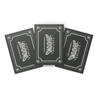 Four Casting Shadows: Card Sleeves from Unstable Games fanned out on a white surface, displaying the word "shadows" in a decorative font on a gray and black ornate background.