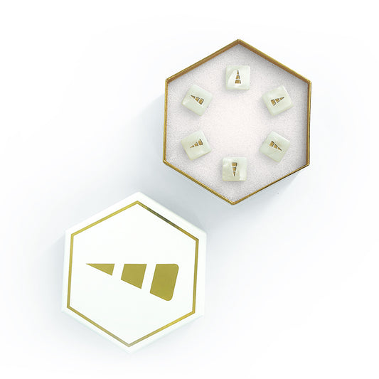 Top view of an open hexagonal game box with small triangular prism gift boxes arranged inside it, isolated on a white background showcasing Unstable Unicorns: White D6 Dice Set by Unstable Games.