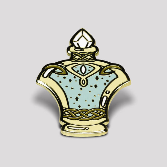 An ornate enamel pin designed to look like a Golden Potion Bottle Pin with intricate gold detailing and turquoise accents on a gray background by Unstable Games.