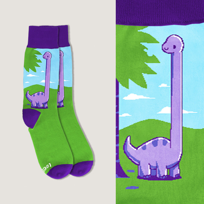 A pair of Bad Day Bronto Socks from Unstable Games, in bright green cotton polyester spandex with purple accents, featuring a cartoon design of a long-necked dinosaur in a scenic landscape.