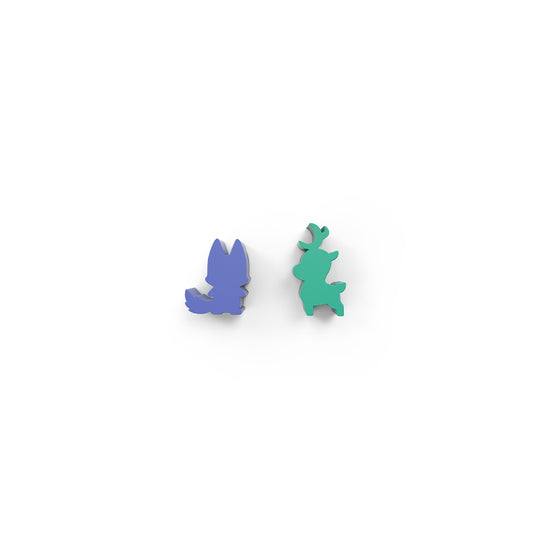 A pair of blue and green animal-shaped pins against a white background. The blue pin resembles a fox, while the green pin, inspired by the Here to Slay: Warriors & Druids Meeples from Unstable Games, resembles a deer.