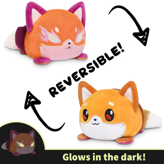 Casting Shadows: Kit Gale & Kit the Turbulent Reversible Plushie by Unstable Games showing two sides: a grumpy orange fox and a happy orange fox, with text highlighting that it glows in the dark.