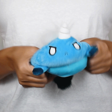 Hands holding and slightly stretching a Tic Tac K.O. Dragons vs. Unicorns: Angy & Tiny Hooves Reversible Plushie of Mudkip, a blue and orange Pokémon, depicted with a playful expression.