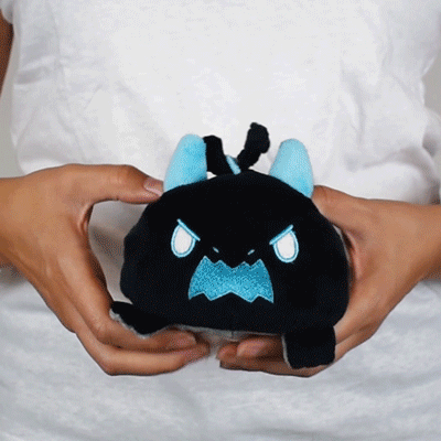 Person holding a Tic Tac K.O. Dragons vs. Unicorns: Lil Grampa Reversible Plushie with a grumpy expression and blue accents from Unstable Games.