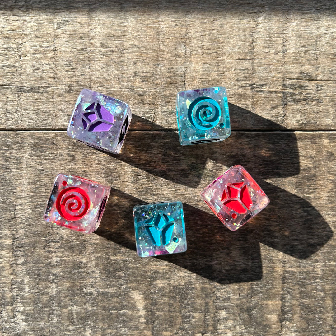 Five colorful, transparent Casting Shadows: Sparkle Core Resource dice with unique symbols, on a wooden surface in sunlight by Unstable Games.