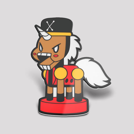 Illustration of a stylized pirate-themed Christmas enamel pin featuring the Nutcracker Unicorn Pin from Unstable Games, complete with a hat adorned with a skull, an eye patch, and a tail resembling a cloud.