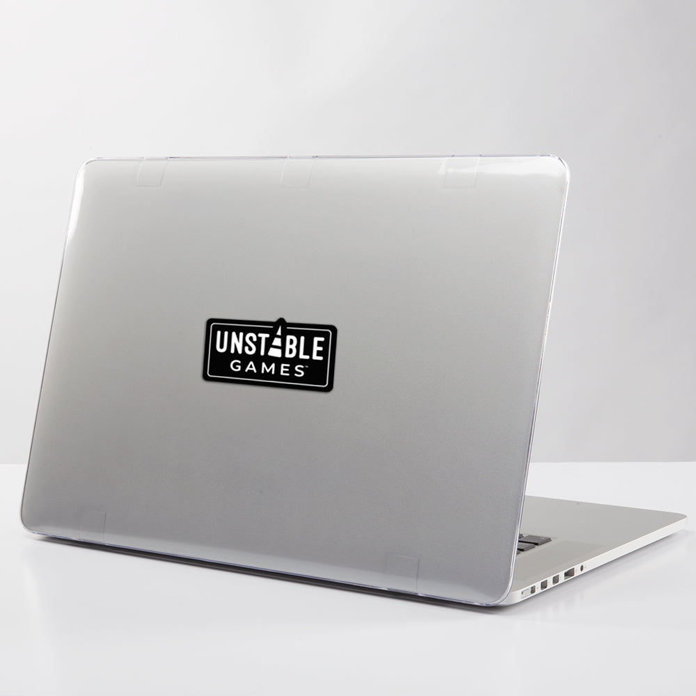 A laptop with a gray cover adorned with an Unstable Games sticker, positioned slightly open on a white surface.