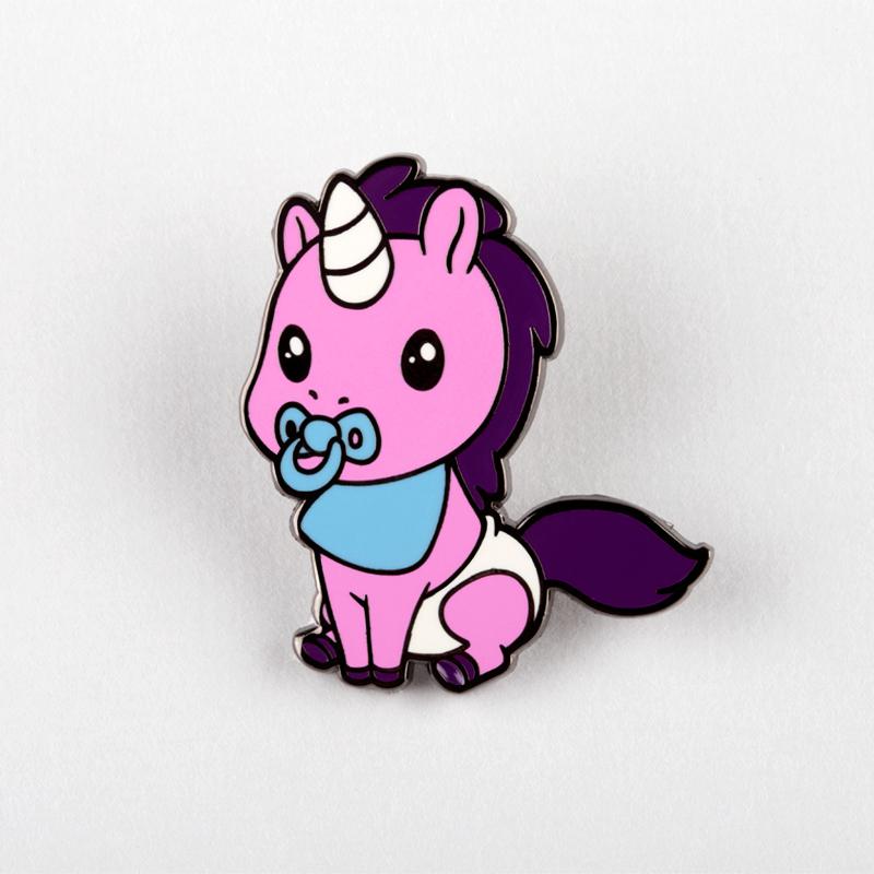 An Baby Unicorn Pin depicting a cartoon-style pink newborn unicorn with a pacifier, sitting against a light gray background by Unstable Games.
